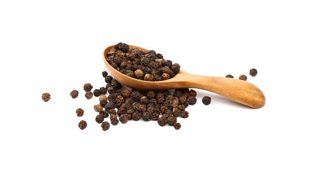 Close up one wooden scoop spoon full of black pepper peppercorns and heap of peppercorns spilled and spread around isolated on white background, high angle view