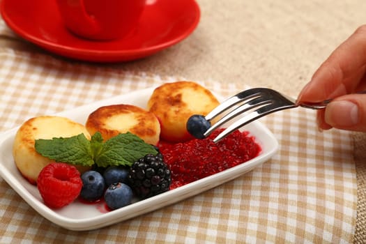 Close up eating European quark cheese pancakes dessert with fruits, high angle view