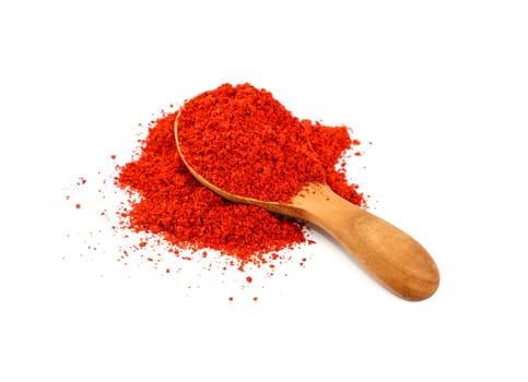Close up one wooden scoop spoon full of red chili pepper, paprika or sundried tomato powder spilled and spread around isolated on white background, high angle view