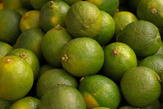 Close up green lime fruits on retail display of farmer market, high angle view