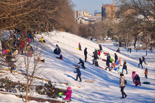 Happy family father, daughter and son are sledding in snow. Happy winter holidays.