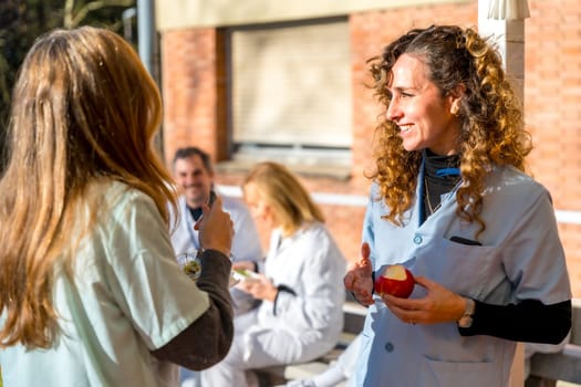 Medical staff eating healthy food during a break outside the hospital during a sunny day