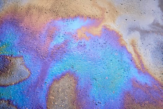 Image of an oil stain on the asphalt of a wet road. Abstract iridescent spots of oil or gasoline