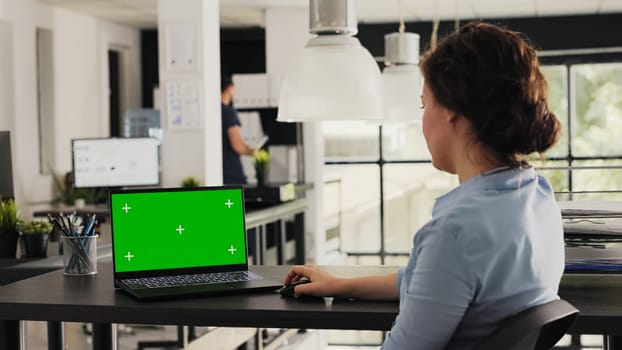 Manager working with greenscreen on laptop, checking isolated mockup template in creative agency office. Young adult looking at pc showing blank chromakey layout on display, modern software.