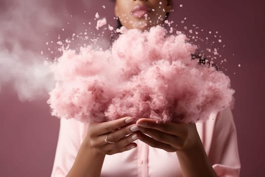 A woman holds a fluffy pink cloud in her hands on a pink background.