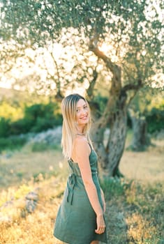 Smiling girl walks in the park, turning back. High quality photo