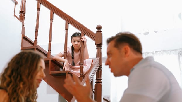 Stressed and unhappy young girl watch her parent arguing from the stair. Domestic violence at home and traumatic childhood develop to depression and anxiety. Unhealthy family concept. Synchronos