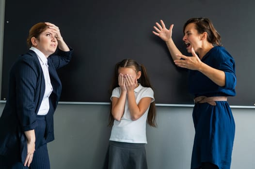 Schoolgirl and her mother yell at the teacher standing at the blackboard