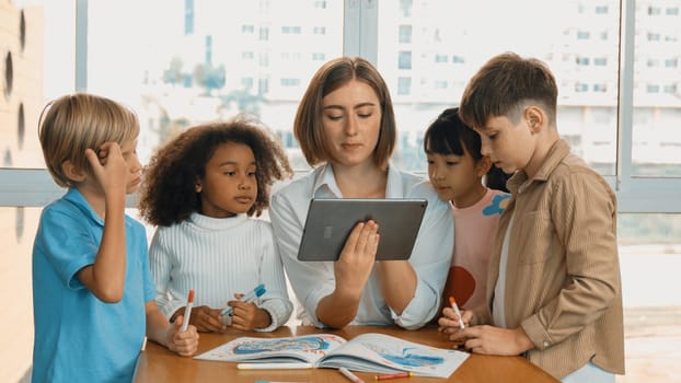 Smart teacher holding tablet while open online lesson to group of students. Skilled instructor explained engineering code lesson while young learner sitting and listening presentation. Erudition.