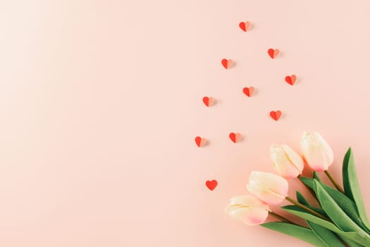Happy Valentines Day background. Top view flat lay of red paper hearts shape and pink tulips flower on pink background with copy space