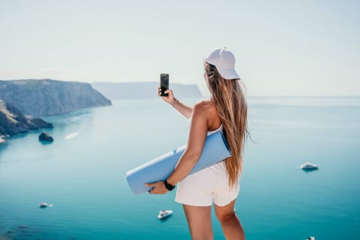 Young woman with black hair, fitness instructor in pink sports leggings and tops, doing pilates on yoga mat with magic pilates ring by the sea on the beach. Female fitness daily yoga concept