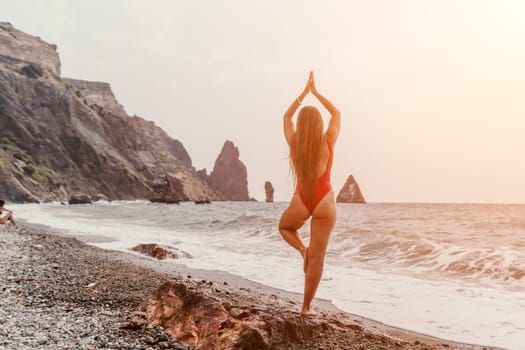 Woman sea yoga. Back view of free calm happy satisfied woman with long hair standing on top rock with yoga position against of sky by the sea. Healthy lifestyle outdoors in nature, fitness concept