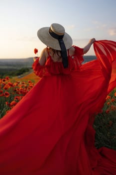 Woman poppy field red dress hat. Happy woman in a long red dress in a beautiful large poppy field. Blond stands with her back posing on a large field of red poppies