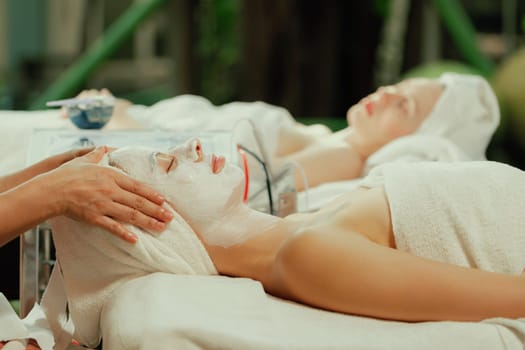 Beautiful young women lie on spa bed while having facial massage from professional doctor. Attractive female with beautiful skin surrounded by electric facial machine. Tranquility.