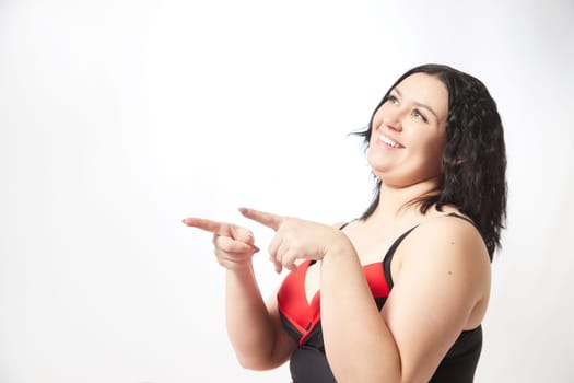 Portrait of attractive dreamy thick woman in red black swimsuit posing on white background. Body positive, photoshoot, selfie. Funny plus size model