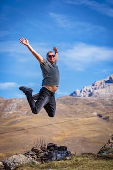 A joyful man on the top of a mountain experiences the flight of the soul and freedom, enveloped in the stunning beauty of the mountainous landscape.