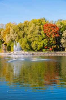 The magical beauty of the autumn park with a fountain on the pond brings peace and quiet.