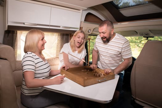 A family of three is playing a board game while sitting in a motorhome.