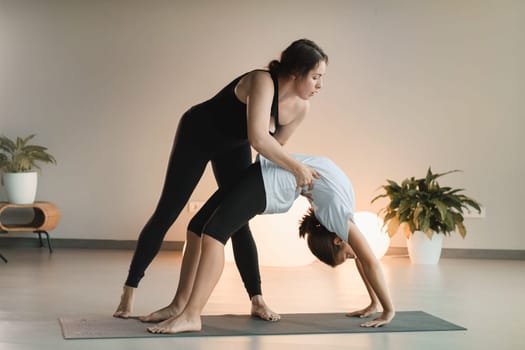 Mom and teenage daughter do gymnastics together in the fitness room. A woman and a girl train in the gym.