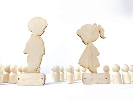 Wooden figures of a girl and a boy against a background of faceless people. A couple in love does not notice anyone around. Love is the most important thing