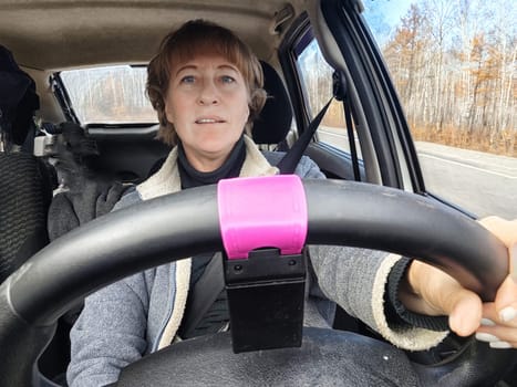 Portrait of female driver in solo journey. Adult mature woman holding steering wheel and looking through windscreen in travel by vehicle on vacation. Lady girl who is owner or rent car for travel