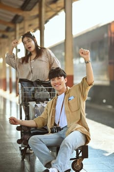 Cheerful young Asian couple arriving at train station while traveling on their vacation. Travel and lifestyle concept