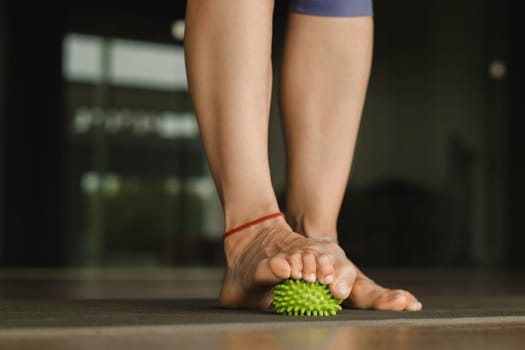 Close - up of the legs of a woman performing gymnastic exercises to correct flat feet during ball massage at home.