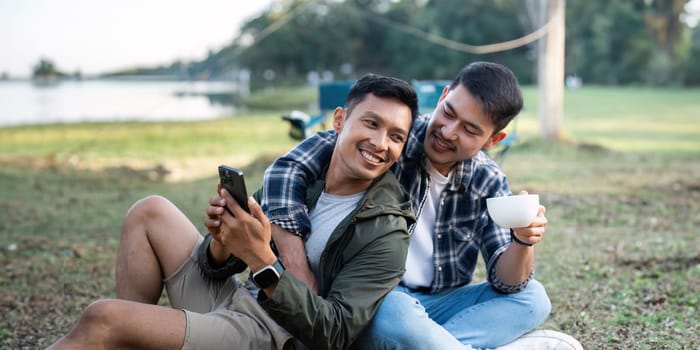 Gay LGBTQIA couple relax and drinking tea and coffee while camping on vacation holiday.