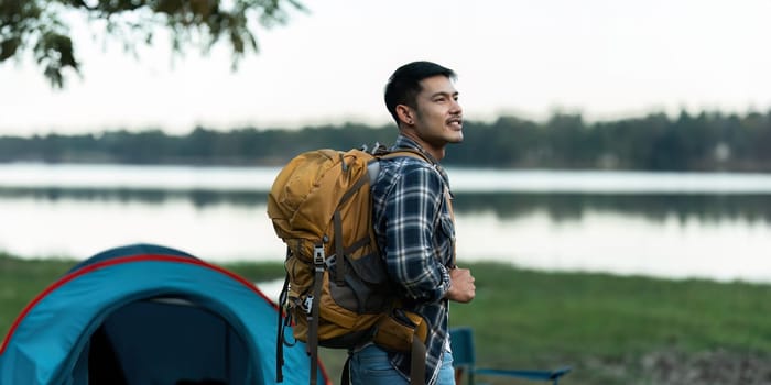 Young man backpacker traveling alone. Attractive male traveler walking in nature wood lake during holiday vacation trip.