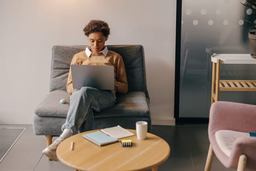 Pretty female freelancer working on laptop while sitting on modern coworking background