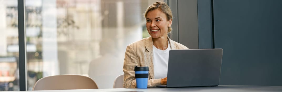 Female sales manager working on laptop while sitting the desk in modern coworking