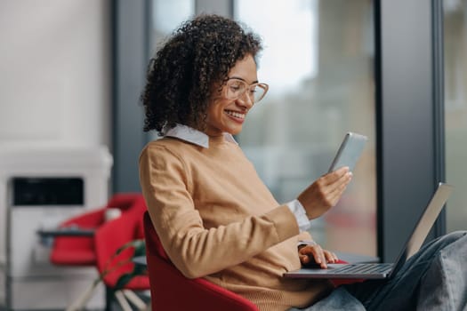 Smiling woman executive manager is using mobile phone sitting in office during break time