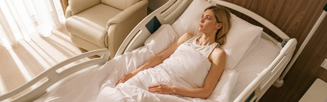 Young woman lying on bed at modern hospital ward after surgery. High quality photo