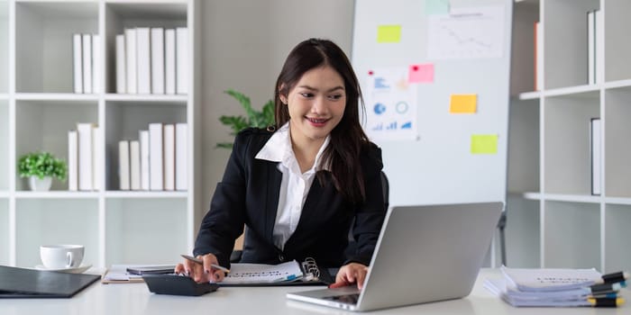 Businesswoman accountant using calculator and laptop for financial data saving in office room, Business financial, tax, accounting concept.