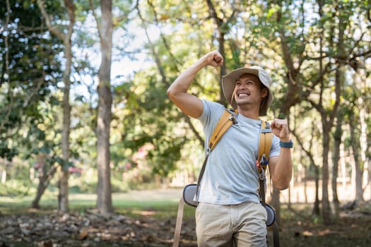 Young man asian trekking among trees with backpack, young man enjoy alone in forest. Camping, hiking, travelling, search for adventure concept.