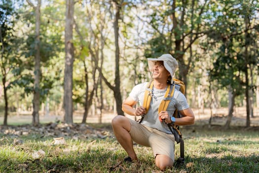 Young man asian trekking among trees with backpack, young man enjoy alone in forest. Camping, hiking, travelling, search for adventure concept.