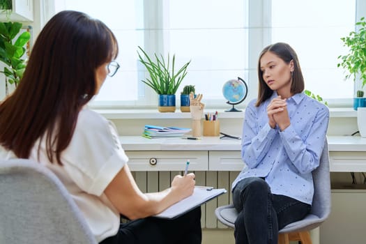 Sad stressed young woman in therapy with professional psychologist. Women talking in office, therapist counselor psychotherapist working with patient. Support, mental health, psychology, psychotherapy