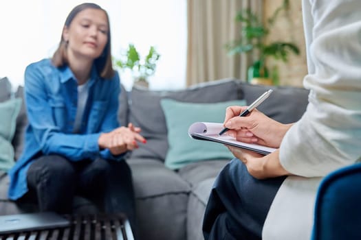 Workplace of counselor psychologist, close-up of hands female mental specialist with clipboard working with female patient. Psychology counseling treatment psychotherapy mental health youth concept