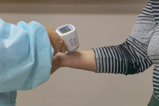 Close up hand of nurse in a disposable medical suit measures body temperature using a medical infrared thermometer. Thermometer gun Isometric medical digital non-contact infrared. soft focus