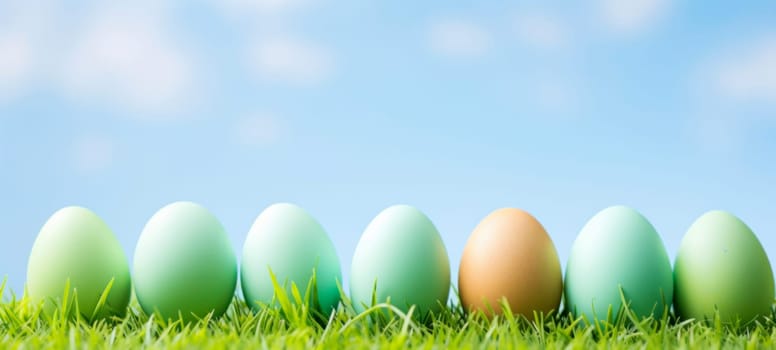 A vibrant display of colorful Easter eggs lined up in a row on lush green grass under a clear blue sky, celebrating the joy of Easter.