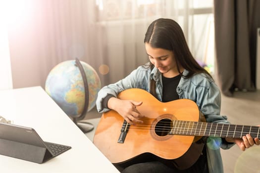 Portrait of smiling teen student practicing guitar during music lessons. High quality photo