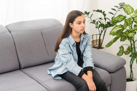 Beautiful young girl sitting on the sofa at home background. Copy space and mock up. High quality photo