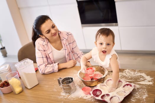 mother and little baby girl preparing the dough in the kitchen, bake cookies. happy time together