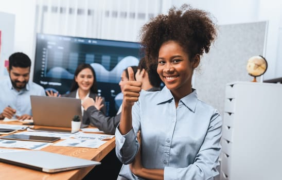 Portrait of happy young african businesswoman with group of office worker on meeting with screen display business dashboard in background. Confident office lady at team meeting. Concord