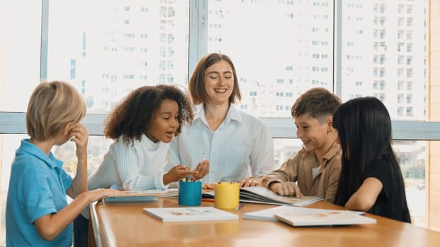 Happy diverse student and smart teacher drawing and coloring by using marker at drawing book. Multicultural smart learner using drawing book while talking to skilled caucasian instructor. Erudition.