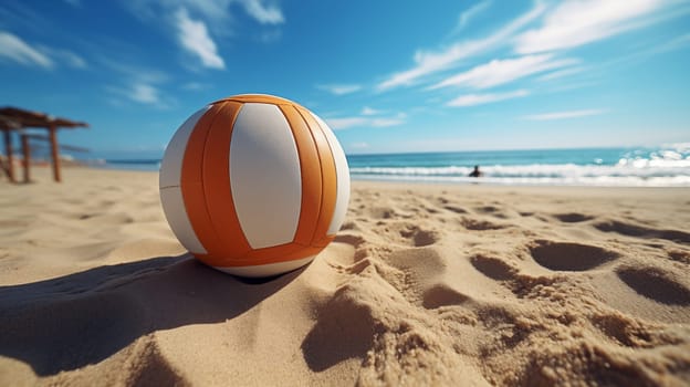 A white-orange volleyball lies on a sandy beach with waves and beachgoers in the blurred background, under a blue sky.