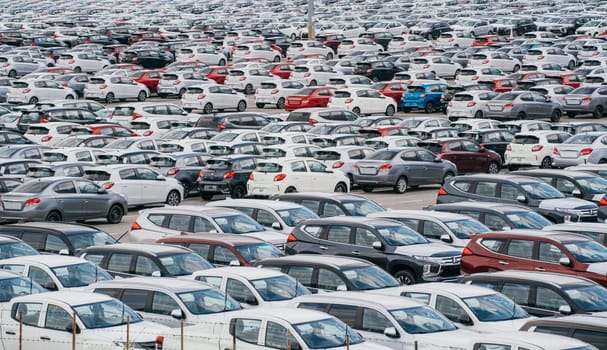 Lamchabang, Thailand - July 02, 2023 Rows of new cars adorn the distribution center of a sunny car factory. The top view unveils a crowded parking area, epitomizing modern industry and business.