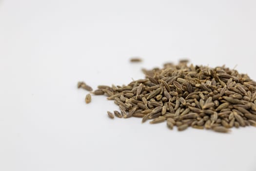 A heap of Cumin seeds neatly arranged on a clean and pristine white background