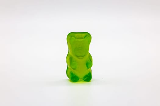 Isolated green gummy bear, sweet snack concept image.