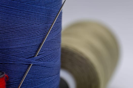 A detailed close-up shot of a needle in a blue thread